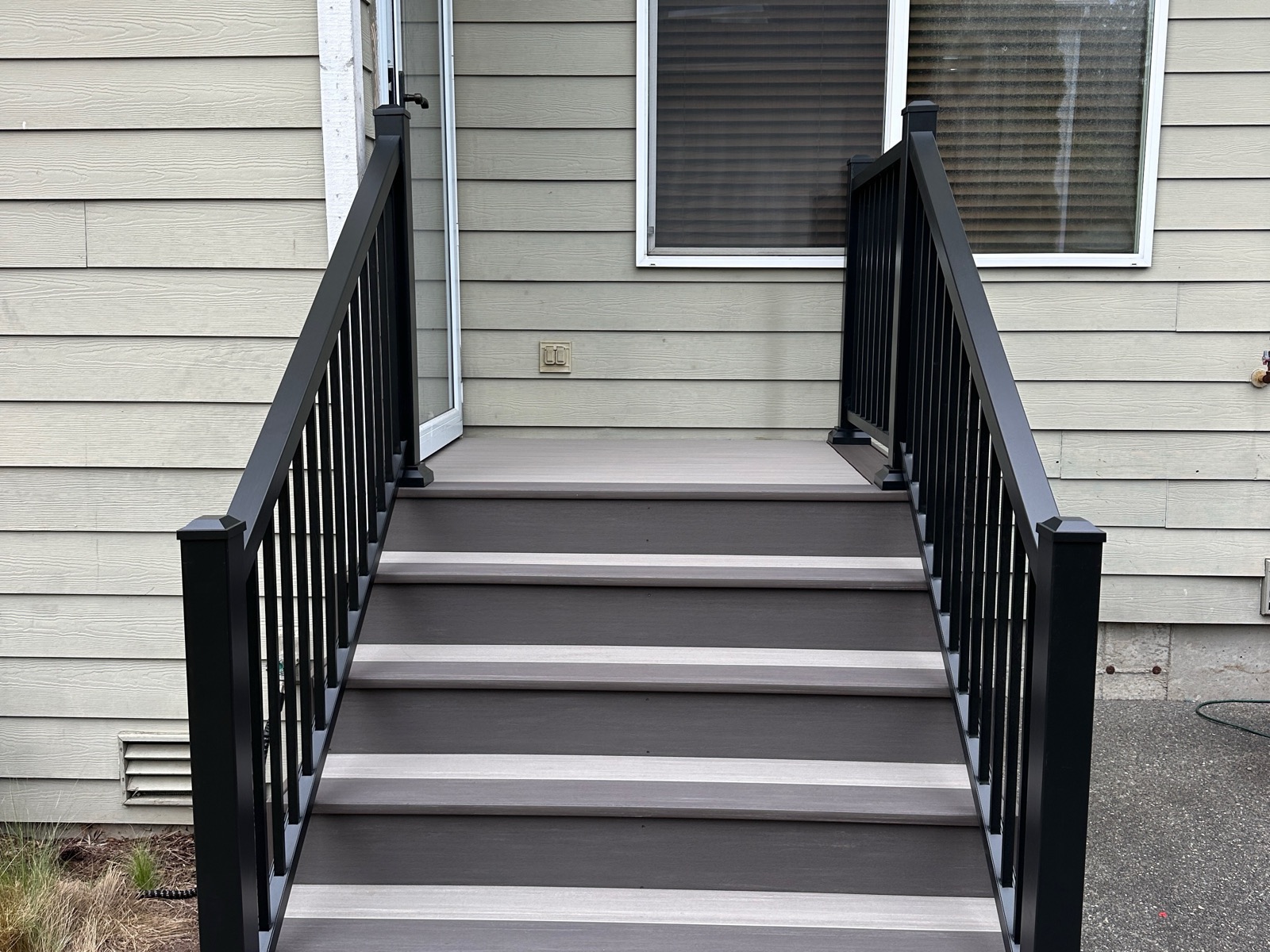 After: Weathered wood entry stairs replaced with composite treads and black aluminum railing
