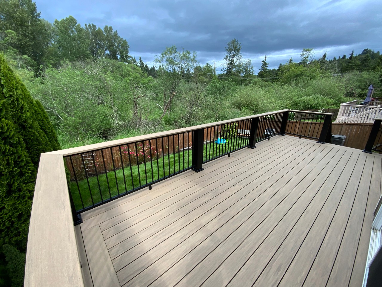 Composite deck with black aluminum railing overlooking a wooded valley