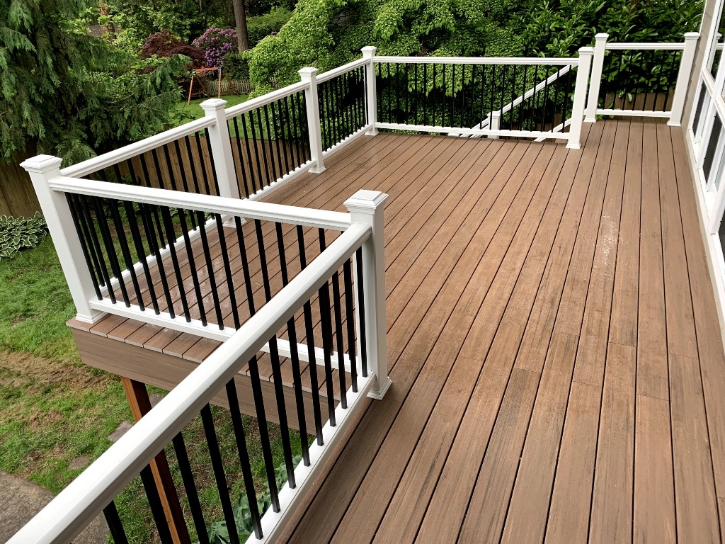 Composite deck with white posts and black balusters in a wooded yard