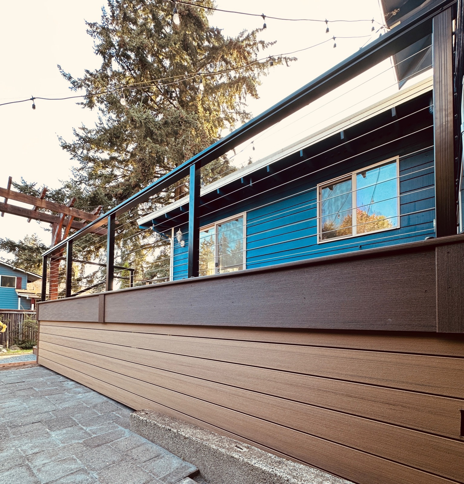 Composite deck with horizontal skirting and cable railing on a blue home