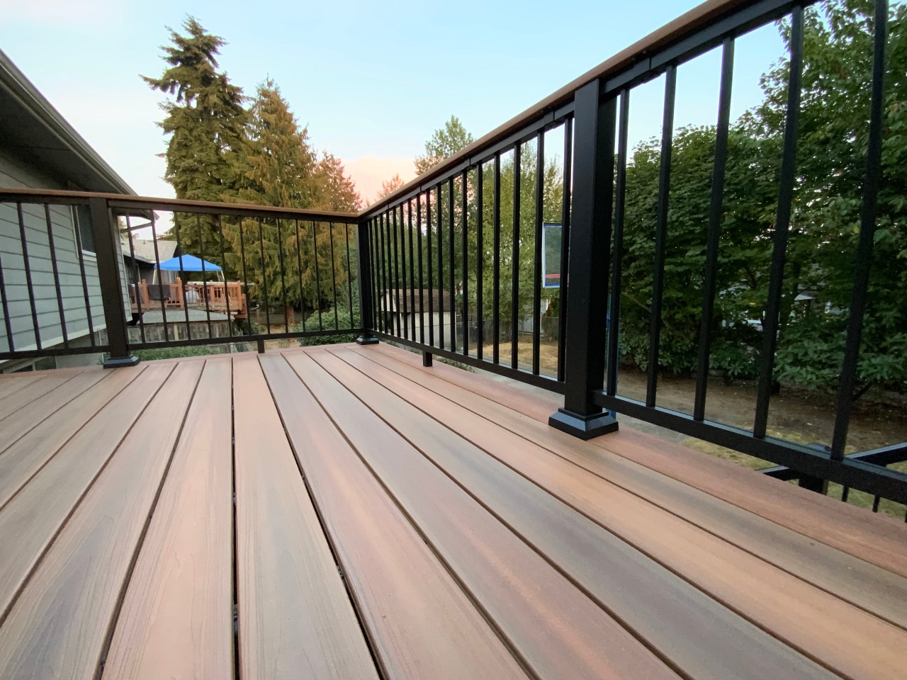 Composite decking and black aluminum railing under an evening sky