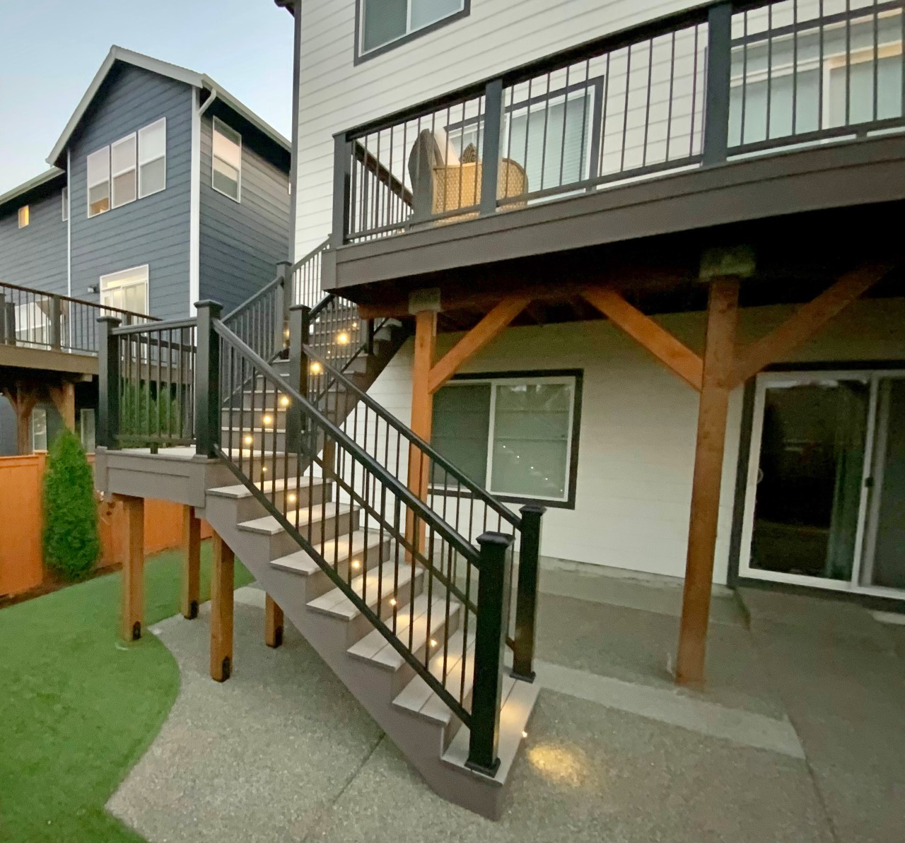 Two-story deck with timber posts and composite stairs on a grey home