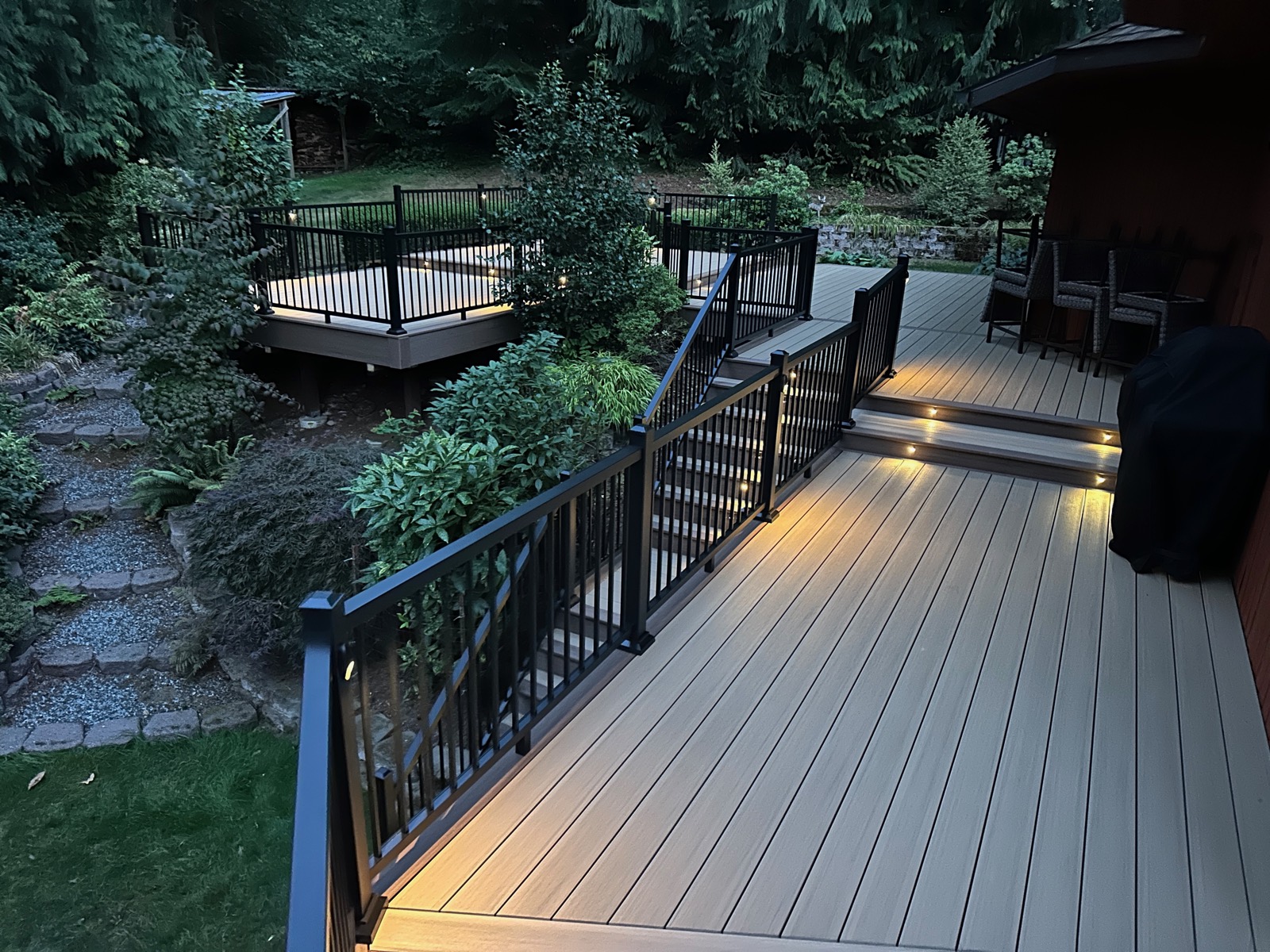 Composite deck, stairs and landing with railing lights on a wooded hillside lot