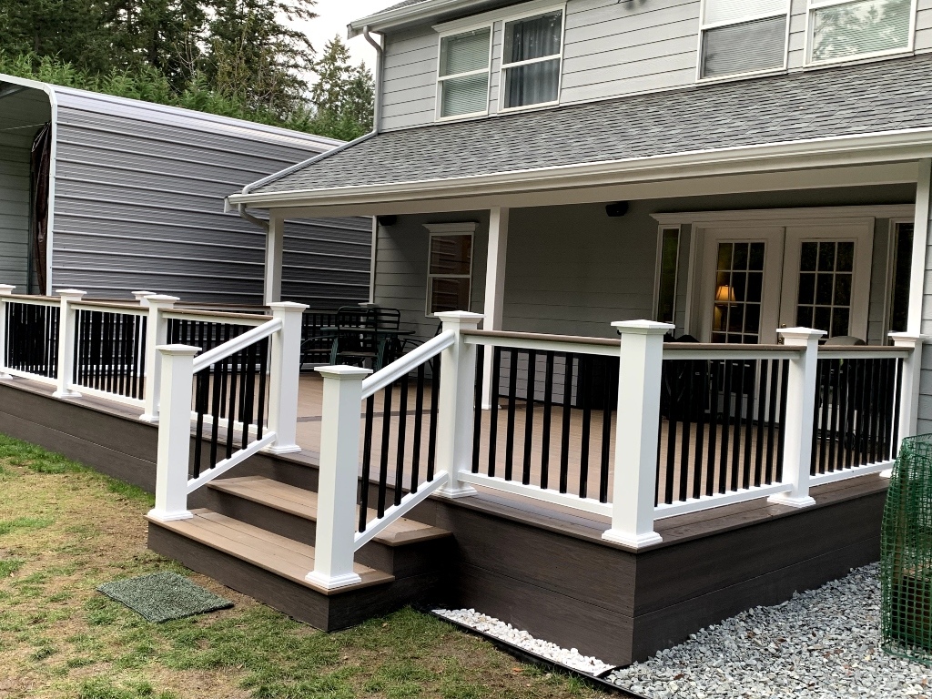 Composite deck with white railing and stairs on a gray two-story home