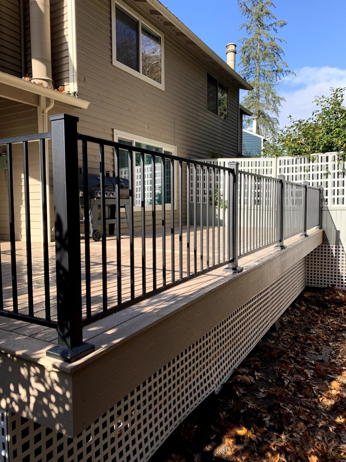 Composite deck with black aluminum railing and white lattice skirting
