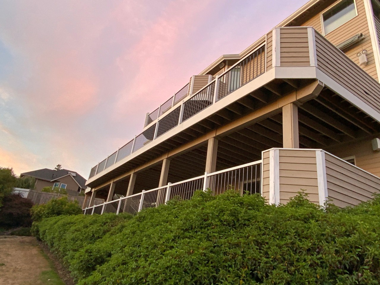 Two-story tan home with a new upper composite deck and railing