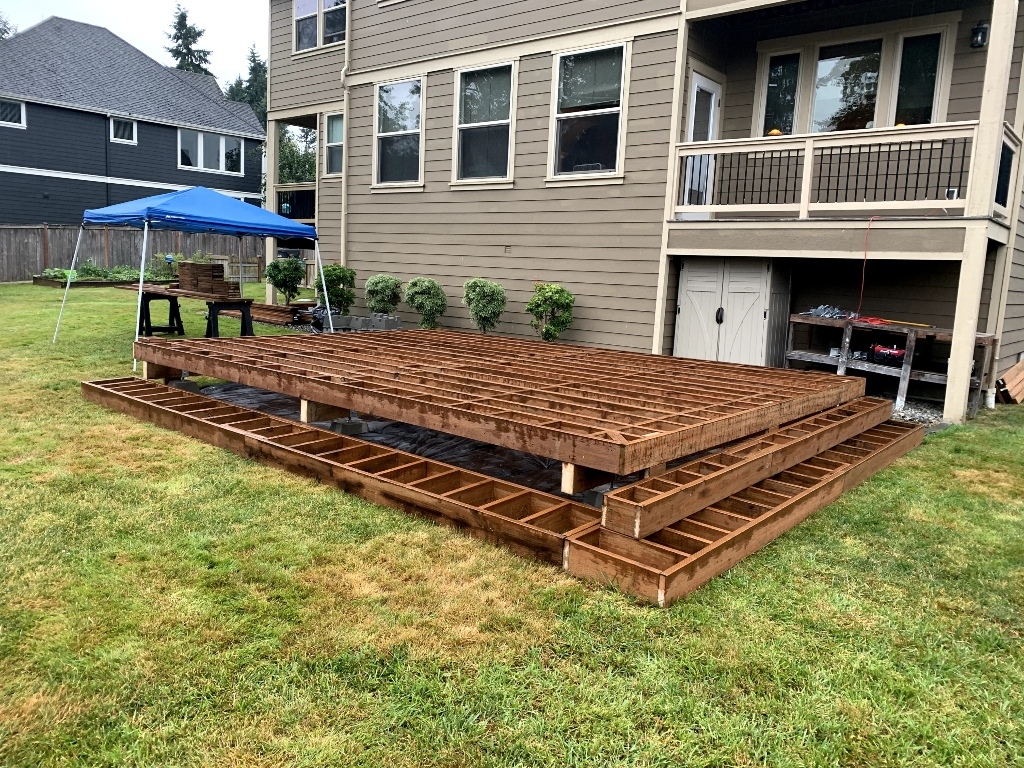 Pressure-treated deck framing on concrete footings before the decking goes down
