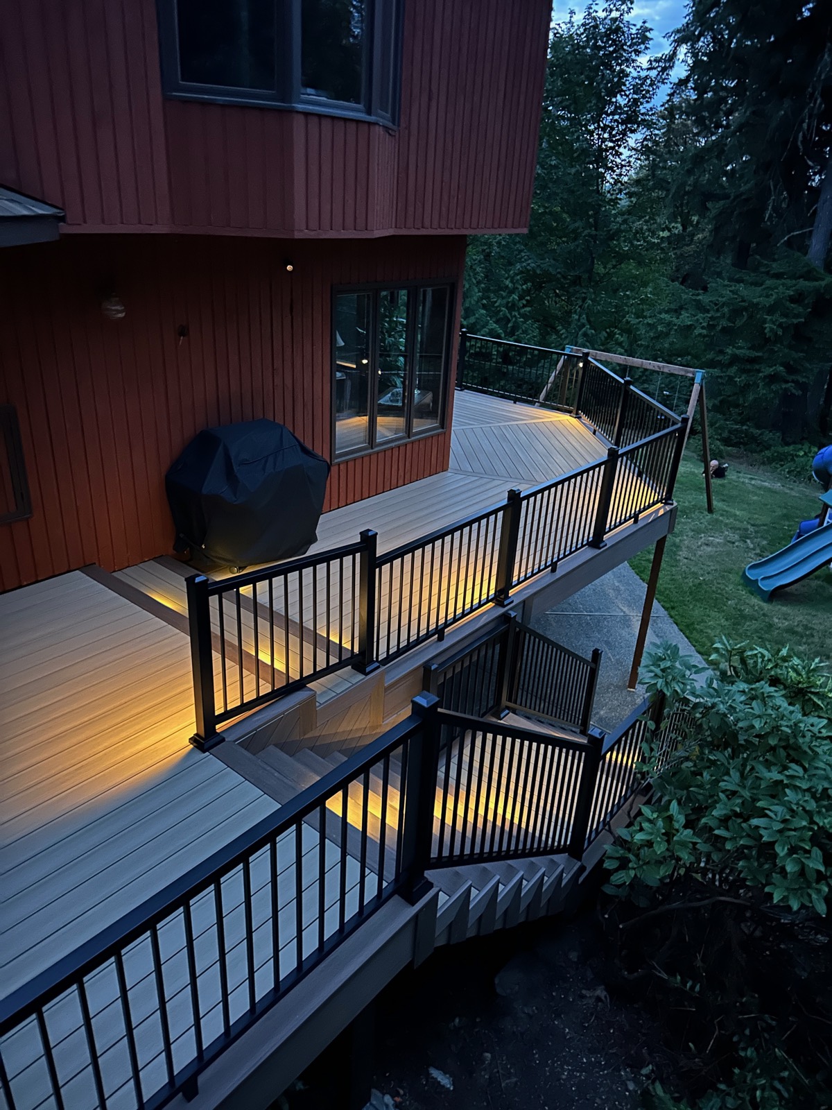 Composite deck with grill area, black railing and stairs down to the yard