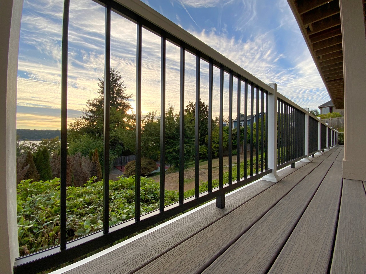 Black aluminum railing on a composite deck with sunset reflections