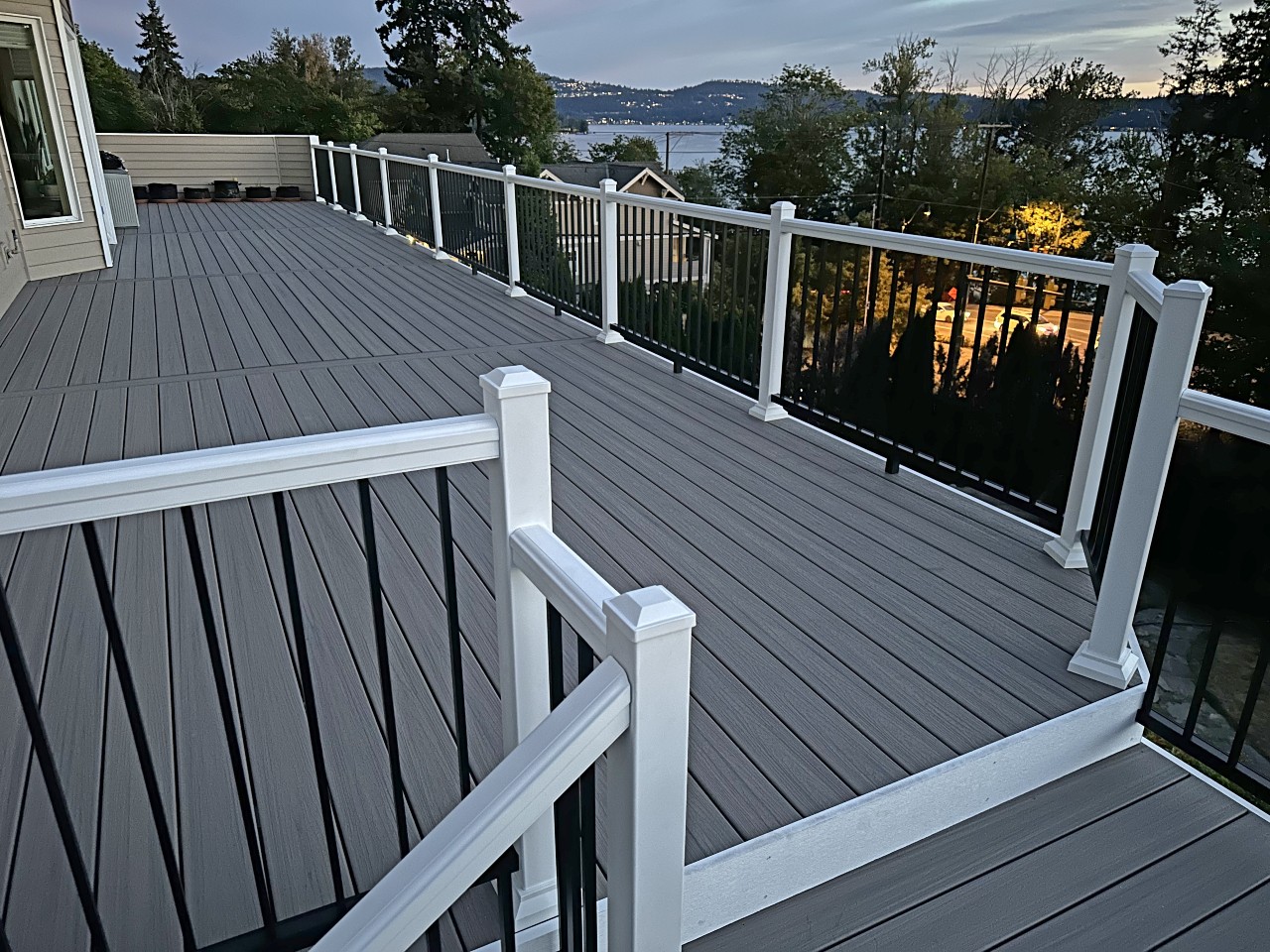 Grey composite deck with white posts and black balusters and a water view