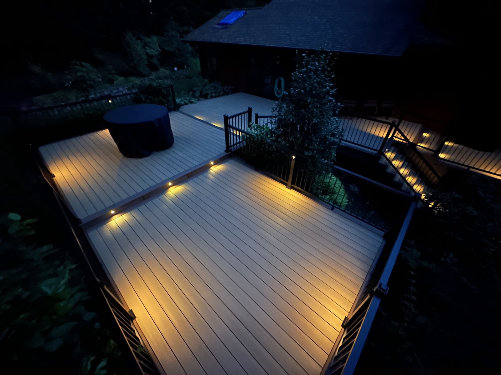 Composite deck with recessed lighting and a hot tub cover at night