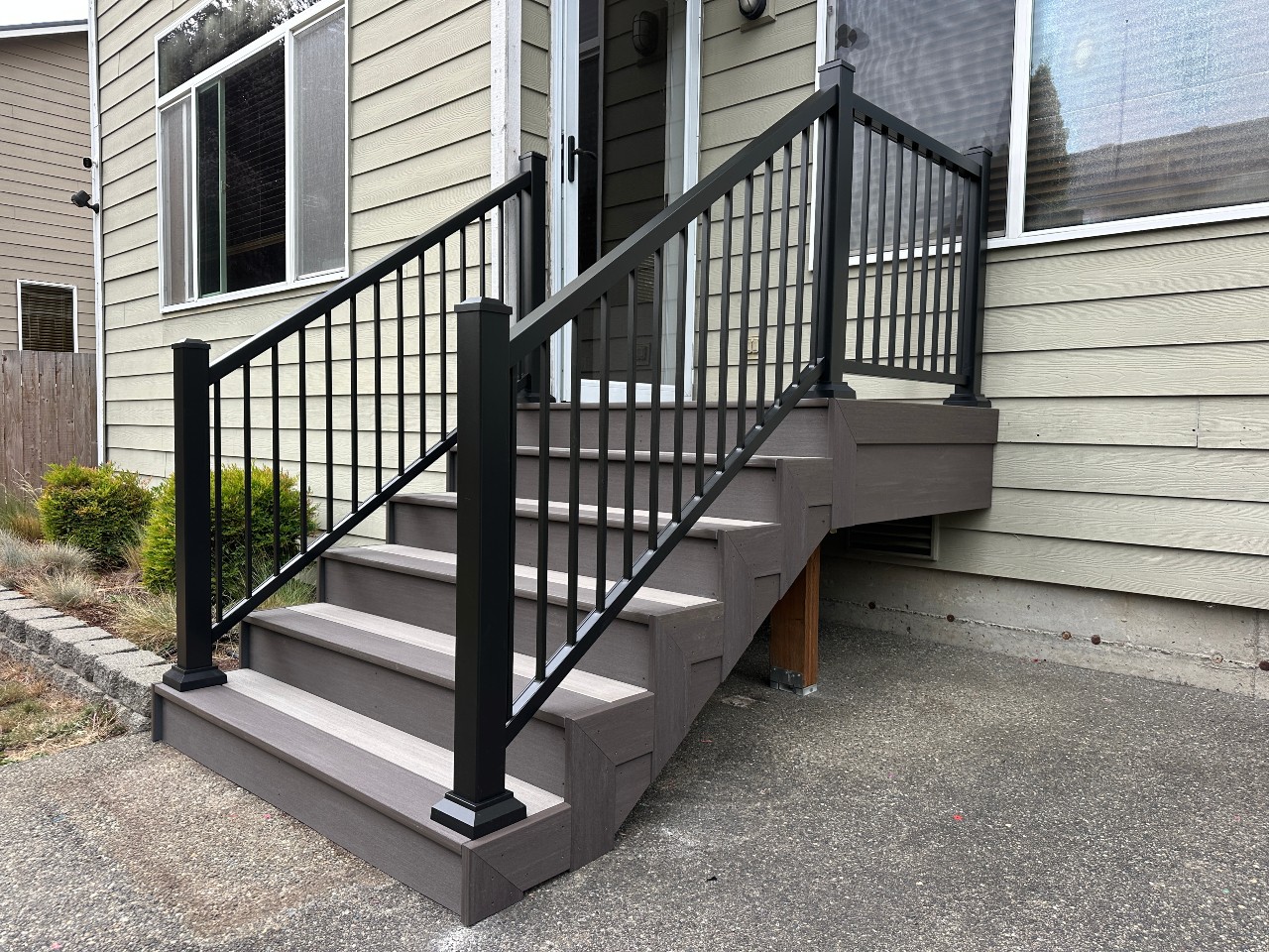 Composite stairs with black aluminum railing on a tan home